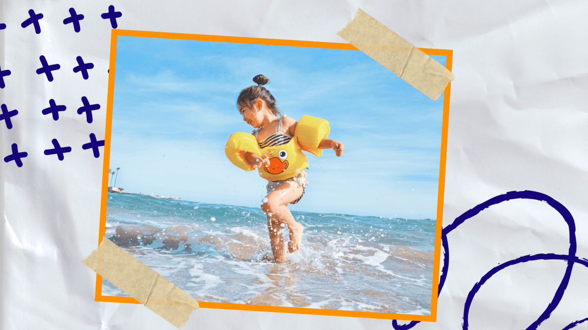 Ein Kind am Strand mit Schwimmlügeln und einem Schwimmring